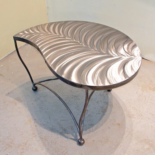 A metal table with a leaf design on top.