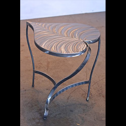 A metal table with a leaf design on top.