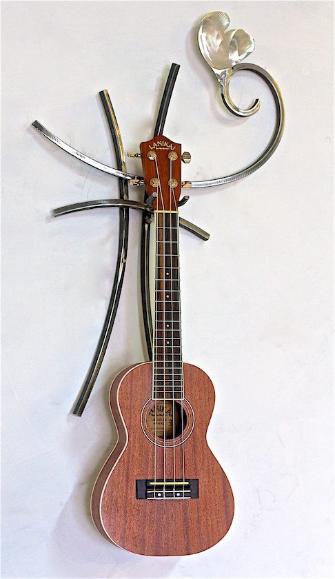 A ukulele hanging on the wall with two wires attached to it.