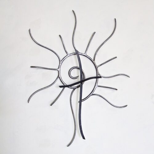 A metal sculpture of an abstract sun with a spiral.