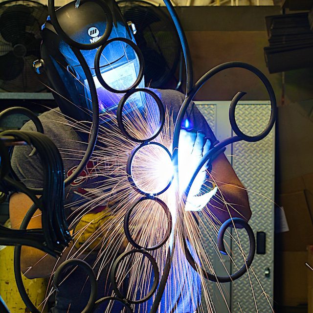 A person welding metal with a large amount of sparks.