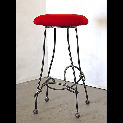 A red stool with metal legs and wheels.