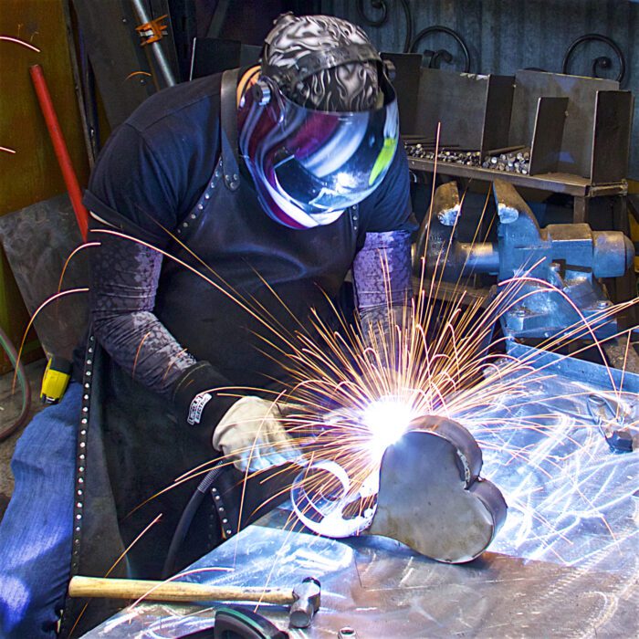 A man welding metal with sparks flying from his hands.