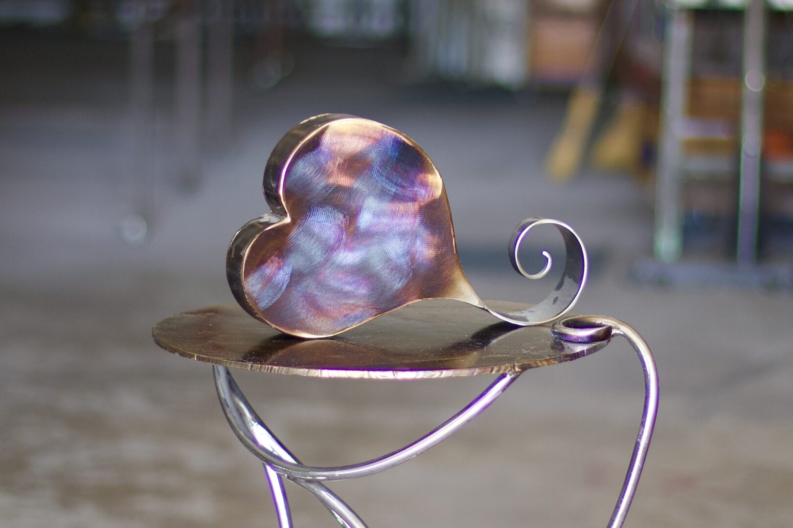 A metal heart sitting on top of a table.