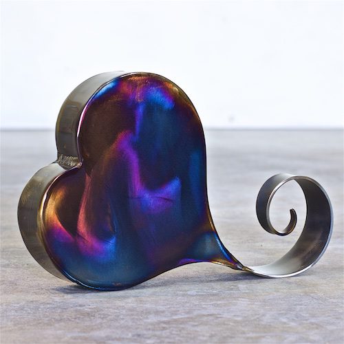A metal heart with a curled tail on top of it.