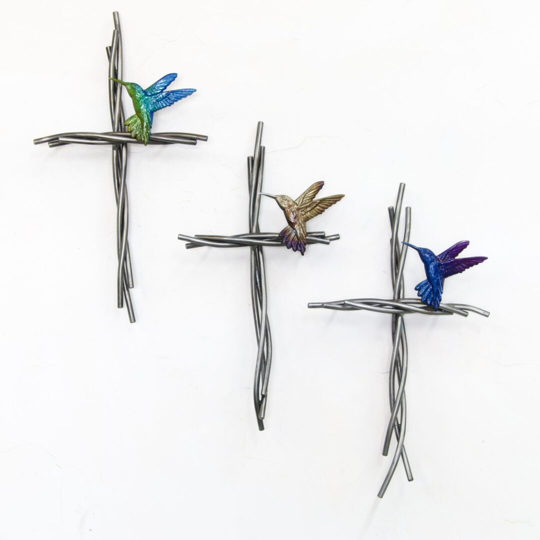 Three crosses with a hummingbird on them hanging from the side of each cross.