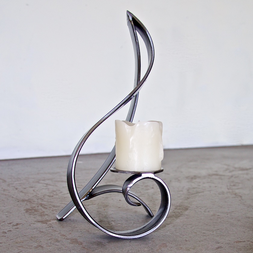 A candle holder with a white pillar and metal swirl.