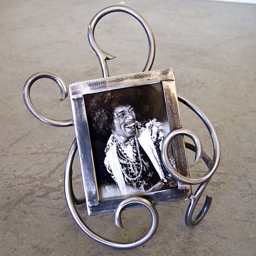 A picture frame with metal curls and a man 's face.