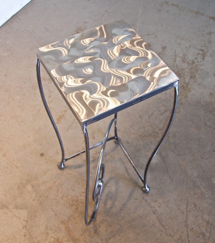 A metal table with a metallic top on the floor