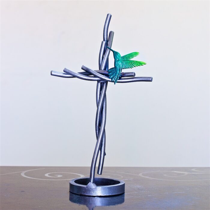 A metal cross with a green butterfly on it.