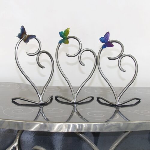 A set of three metal hearts with butterflies on them.