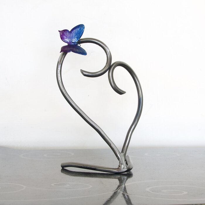 A metal sculpture of a heart with a butterfly on it.