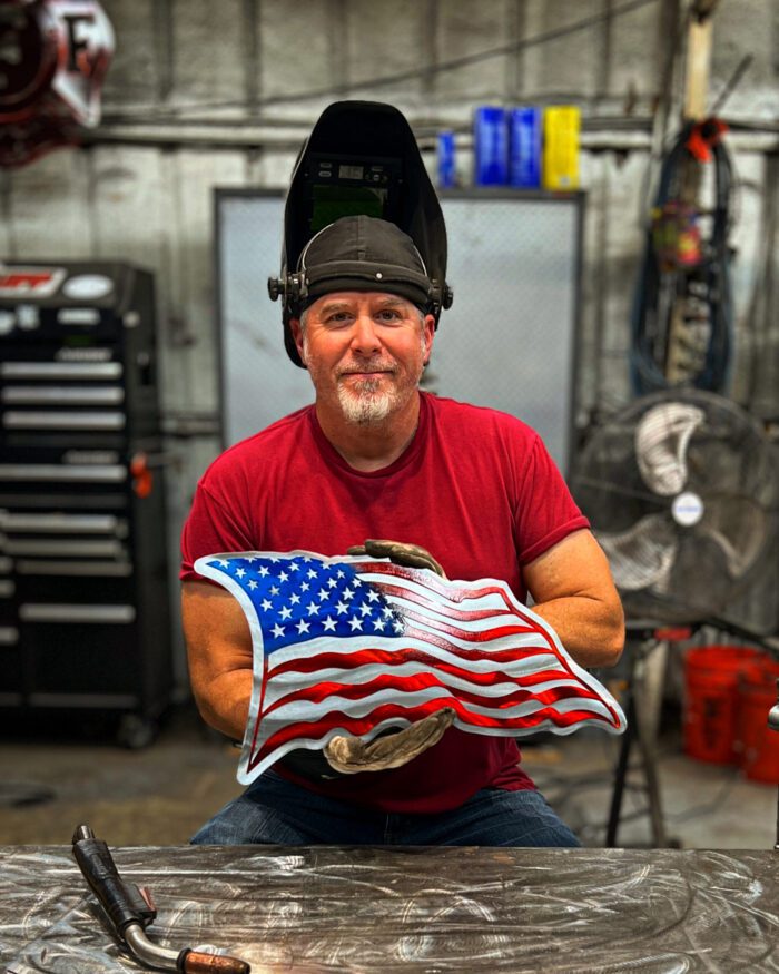 A man holding an american flag pillow in his hands.